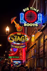 Nashville, Tennessee, USA - April 5, 2013: Colorful signs hang outside Honky Tonk bars and restaurants on Broadway in downtown Nashville, Tennessee. A crowd of people walk below.